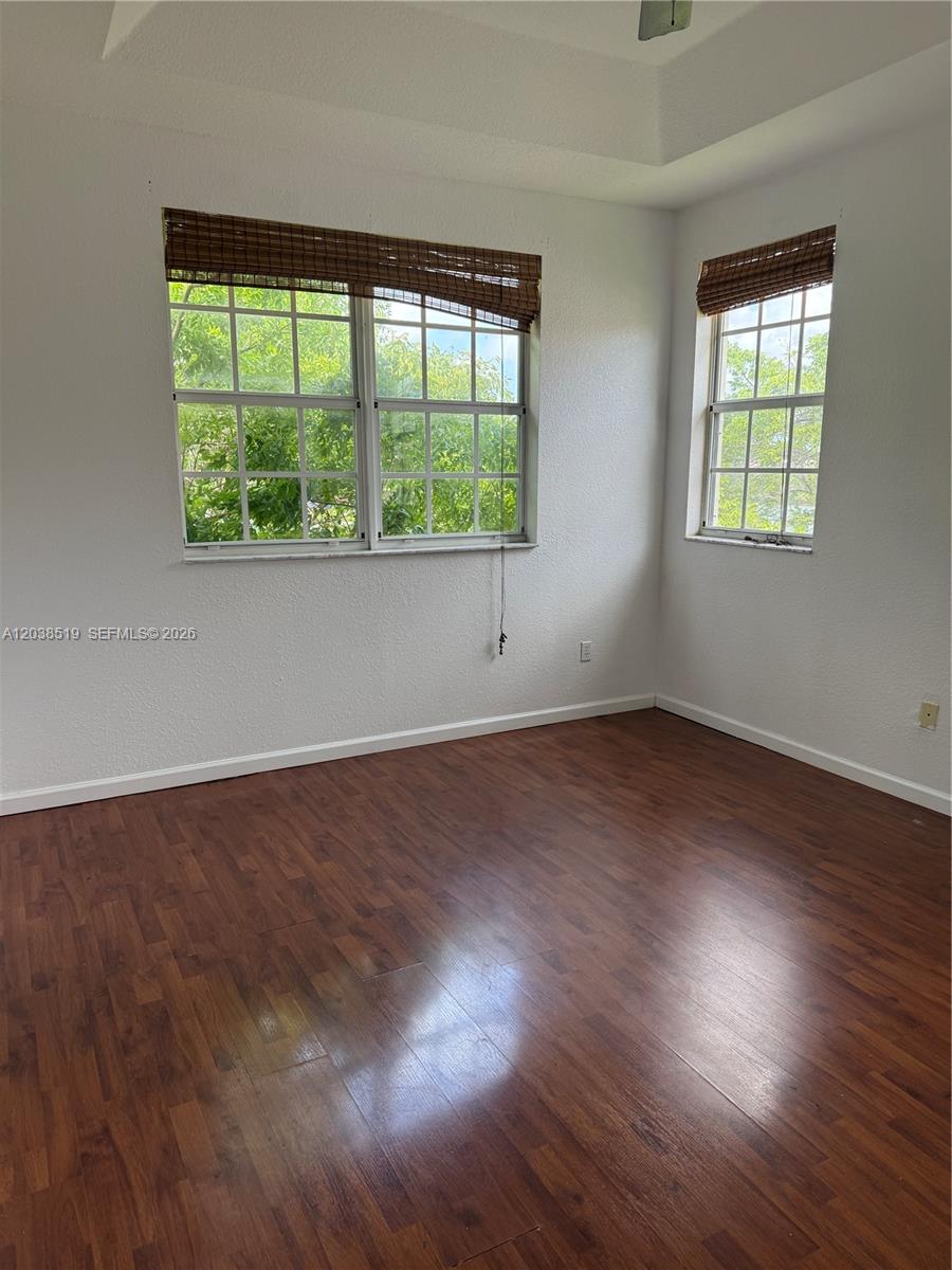 An empty room features wood-look flooring, white walls, and two windows with bamboo shades — 551 NE 21st Ter, Homestead FL 33033, HOMESTEAD, FL