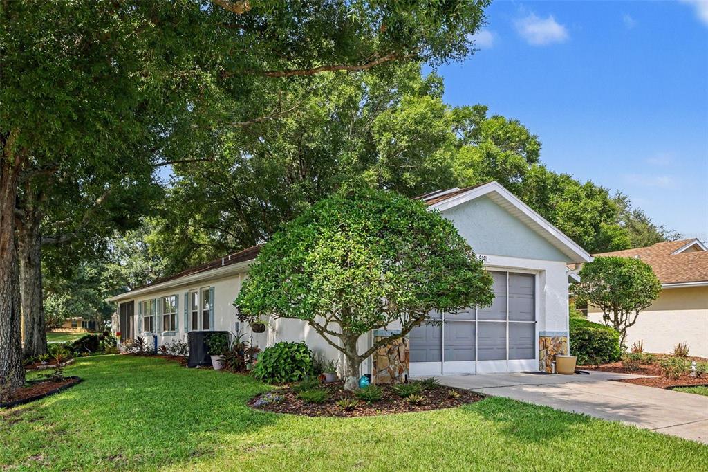 A single-story house with a garage, stone accents, and a large tree in the yard — 9141 SW 91ST CIRCLE, OCALA, FL
