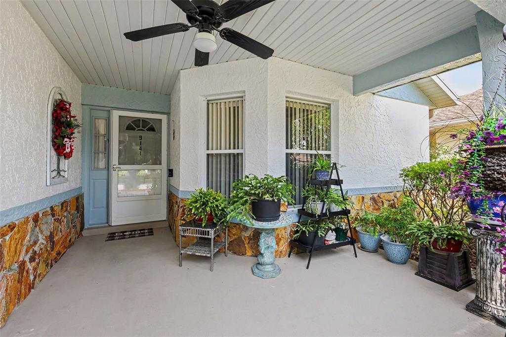 A covered front porch features a ceiling fan, stone siding, and several potted plants — 9141 SW 91ST CIRCLE, OCALA, FL