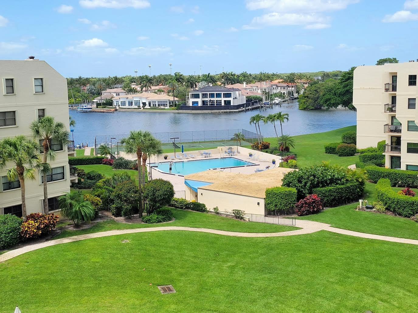 An elevated view of a swimming pool, green lawn, and canal with waterfront homes — 370 Golfview Road # 503, North Palm Beach FL 33408, NORTH PALM BEACH, FL