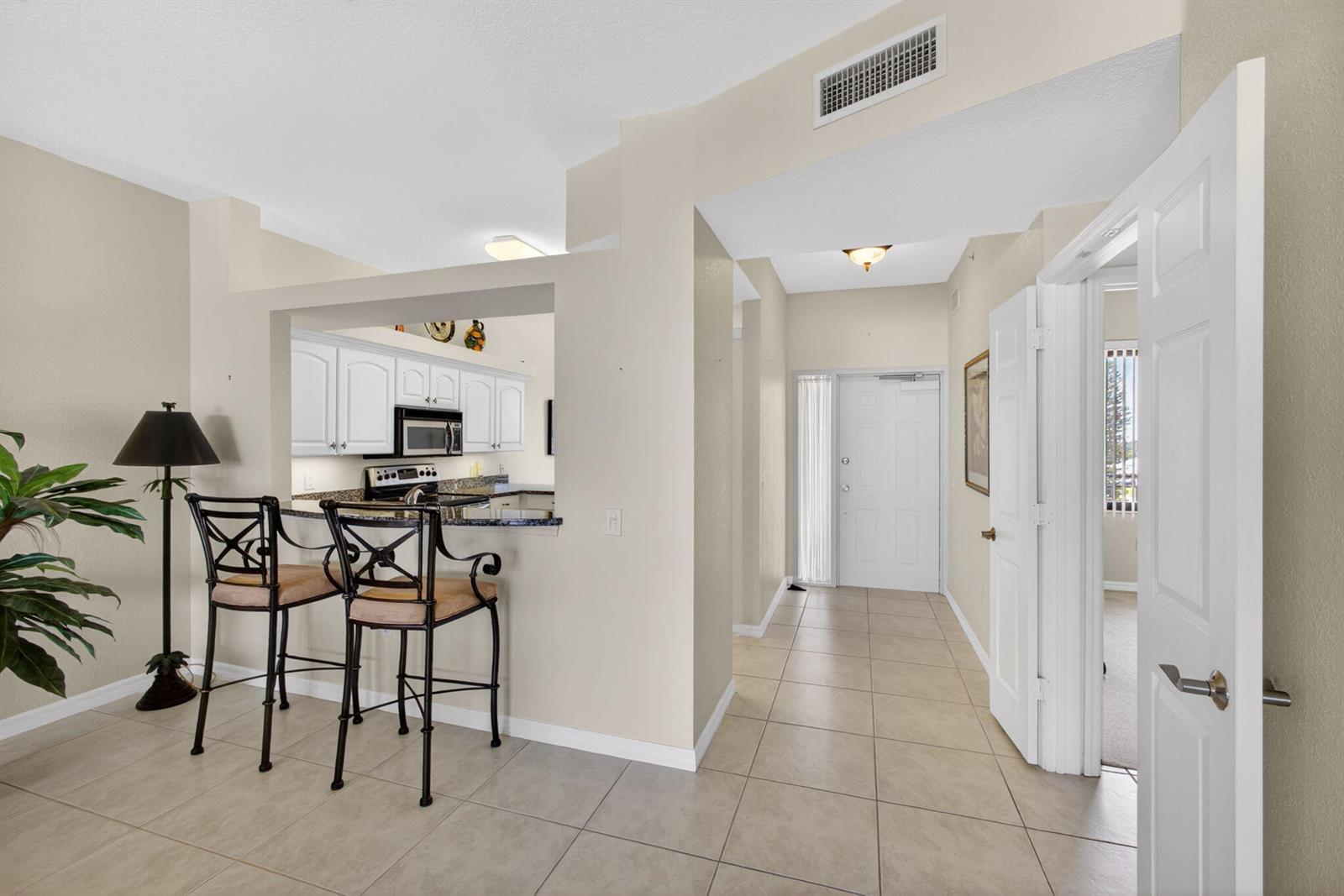A kitchen pass-through with bar seating overlooks a tiled entryway with a front door — 370 Golfview Road # 503, North Palm Beach FL 33408, NORTH PALM BEACH, FL