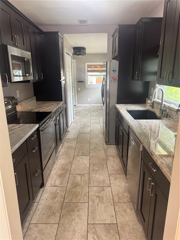 A galley kitchen features dark wood cabinets, granite countertops, and light-colored tile flooring — 1701 53RD STREET S, GULFPORT, FL