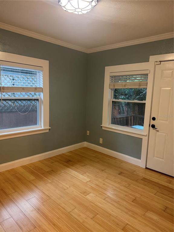 A room with blue walls, light wood flooring, two windows, and a white exterior door — 1701 53RD STREET S, GULFPORT, FL