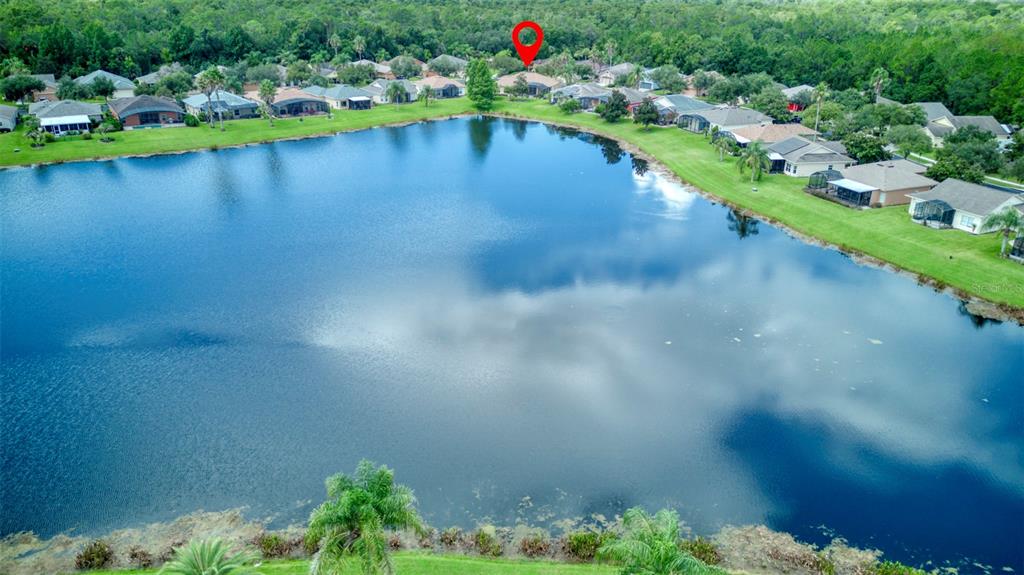 An aerial view shows a residential neighborhood with houses situated along the edge of a lake — 392 DAVINCI PASS, POINCIANA, FL