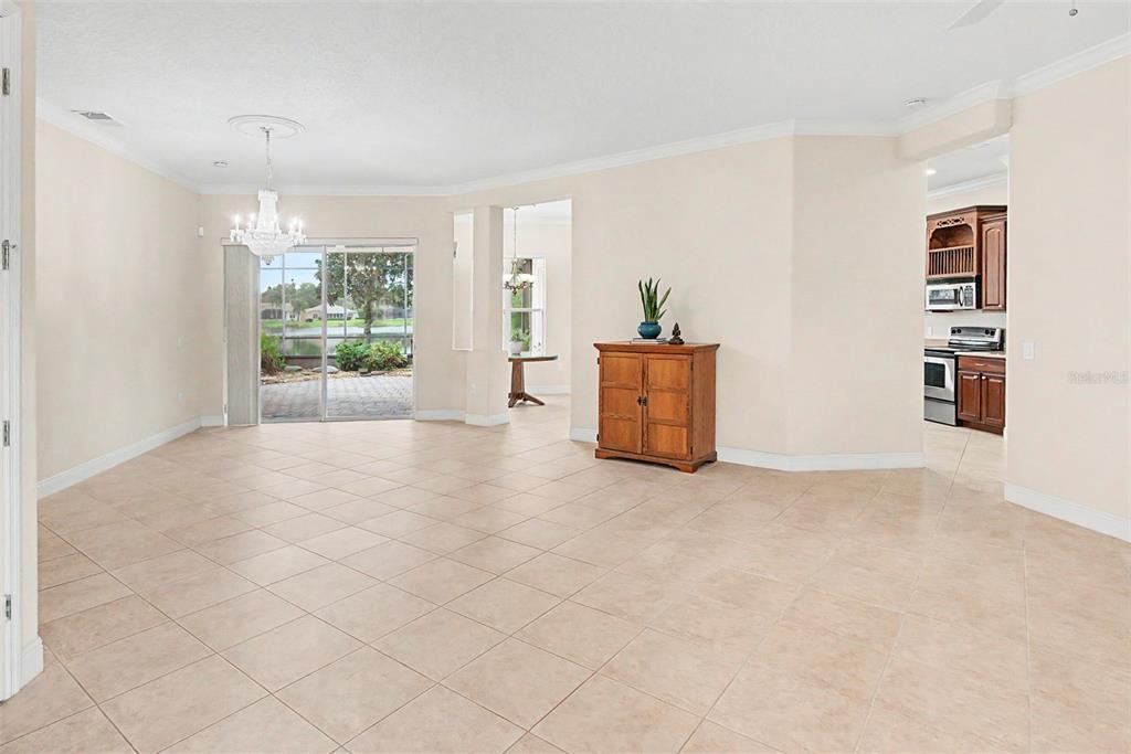 A spacious living area with tile floors, a crystal chandelier, and a view of a lake — 392 DAVINCI PASS, POINCIANA, FL