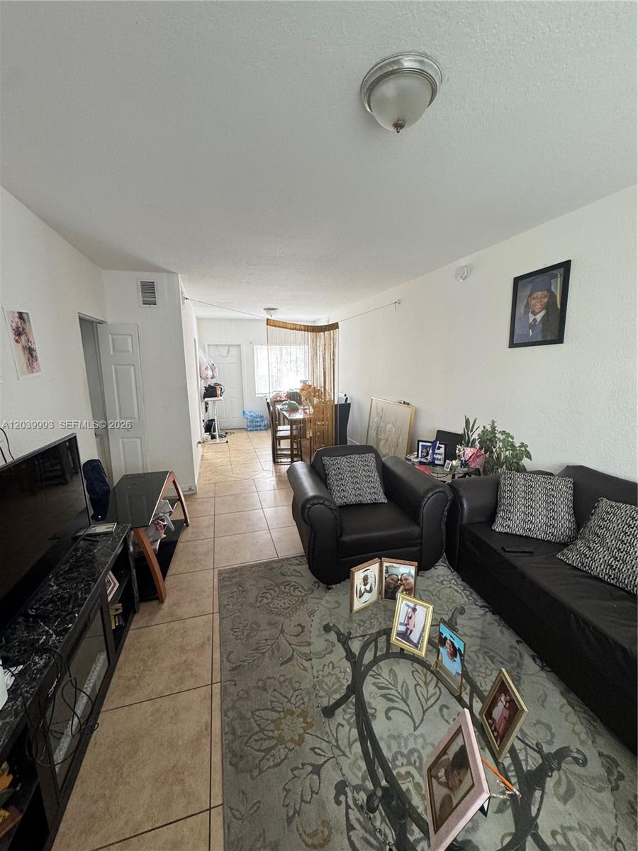 A living room features tile flooring, a black sofa and armchair, and a dining area — 8456 NW 4th Ct # 8456, Miami FL 33150, MIAMI, FL