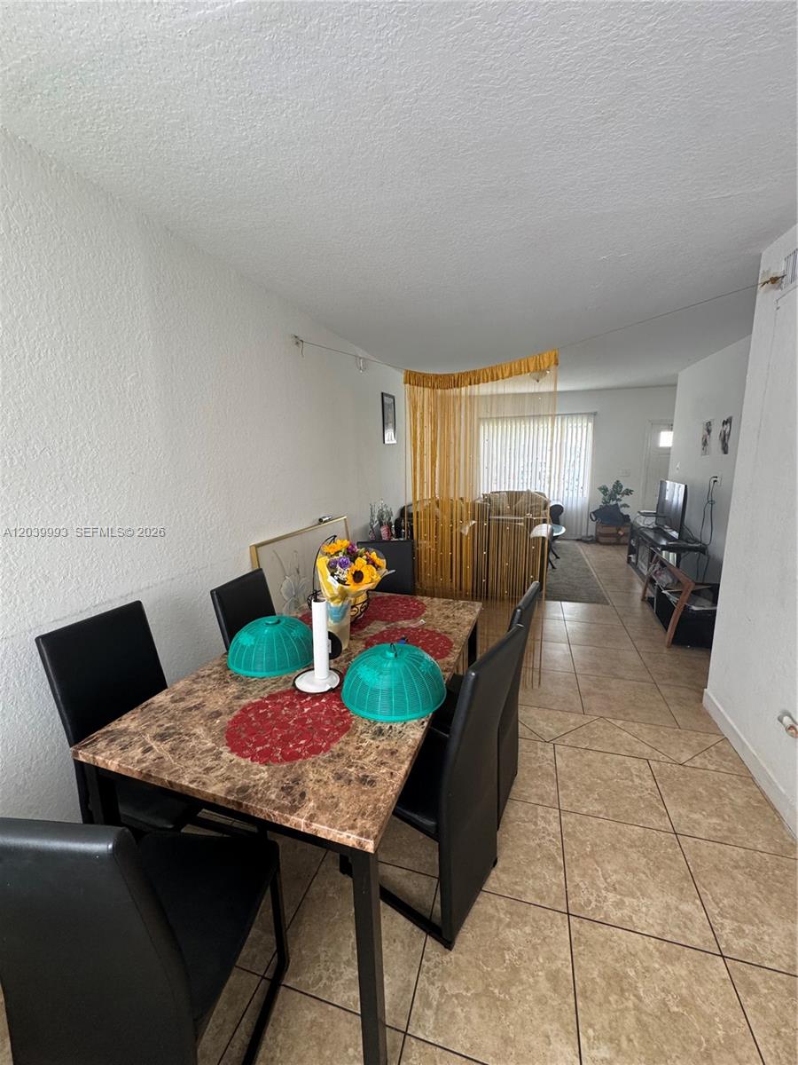A dining area with a marble-topped table sits adjacent to a living space separated by curtains — 8456 NW 4th Ct # 8456, Miami FL 33150, MIAMI, FL