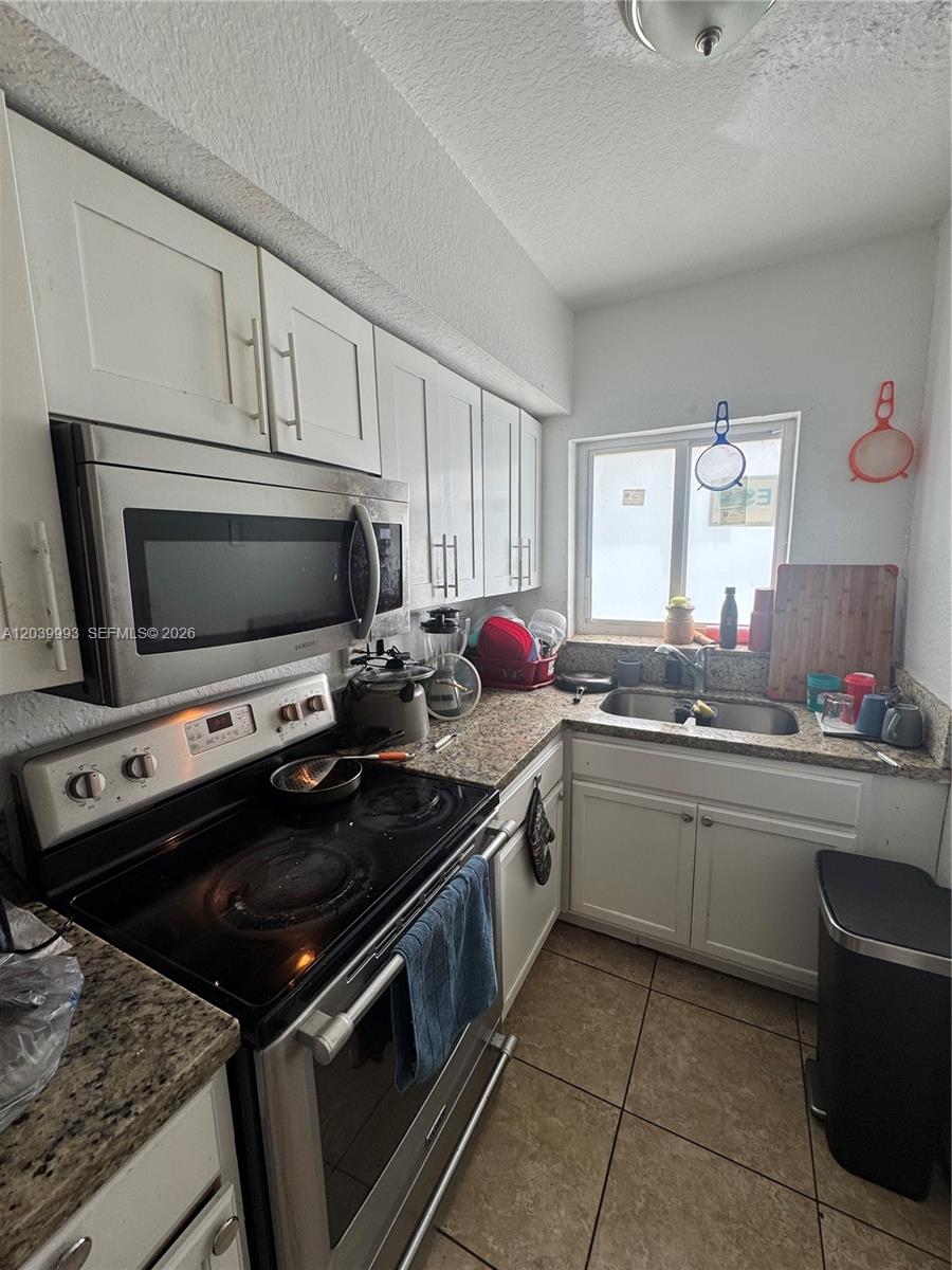 A small kitchen features white cabinets, stainless steel appliances, and granite countertops — 8456 NW 4th Ct # 8456, Miami FL 33150, MIAMI, FL