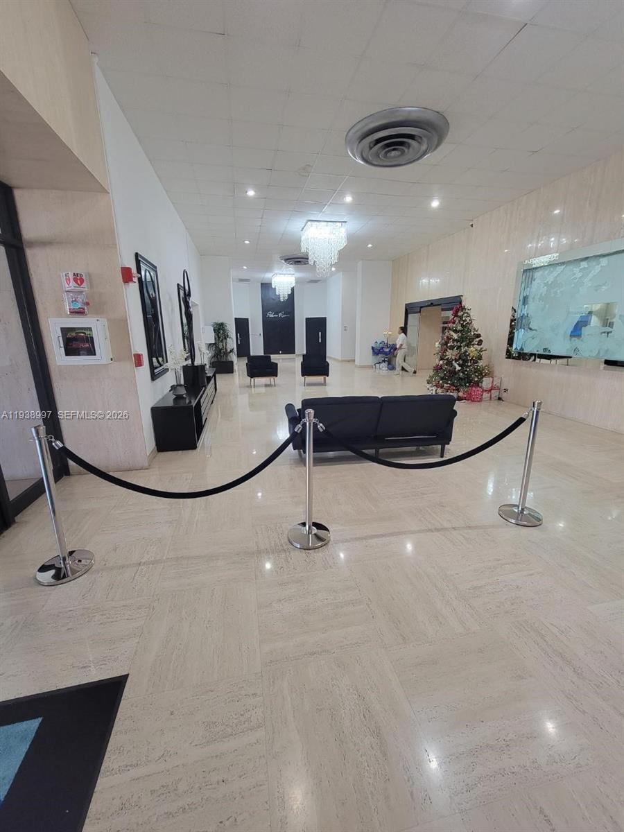 A lobby features marble floors, a dark sofa, stanchions, and a decorated Christmas tree — 500 Three Islands Blvd # 709, Hallandale Beach FL 33009, HALLANDALE BEACH, FL