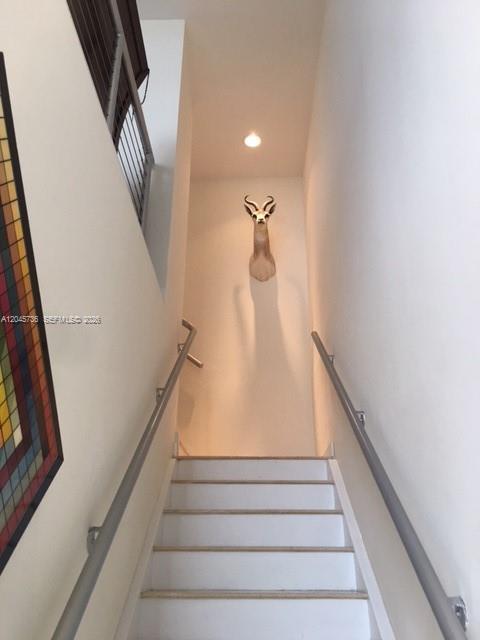 A staircase with white steps and metal handrails leads to a wall featuring an animal mount — MIAMI, FL