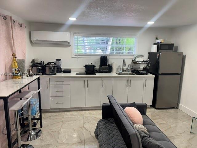 A kitchen features white cabinets, stainless steel appliances, and a breakfast bar with stools — 211 SW 71st Ave, Miami FL 33144, MIAMI, FL