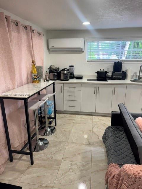 A kitchen features white cabinets, a marble-topped breakfast bar, and a wall-mounted air conditioner — 211 SW 71st Ave, Miami FL 33144, MIAMI, FL