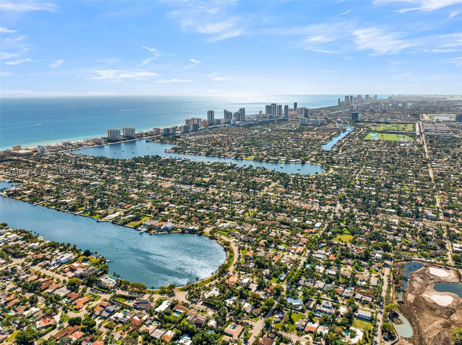 An aerial view shows a coastal residential neighborhood with lakes, palm trees, and distant skyscrapers — 1310 Polk St, Hollywood FL 33019, HOLLYWOOD, FL