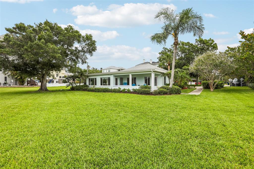 A light-colored house with a screened porch sits on a large, grassy lawn — 610 INDIANA AVENUE, CRYSTAL BEACH, FL