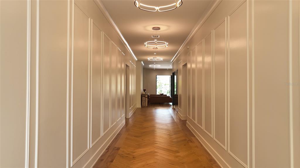 A long hallway features herringbone wood floors, paneled walls, and multiple modern light fixtures — 1220 DELANEY PARK DRIVE, ORLANDO, FL