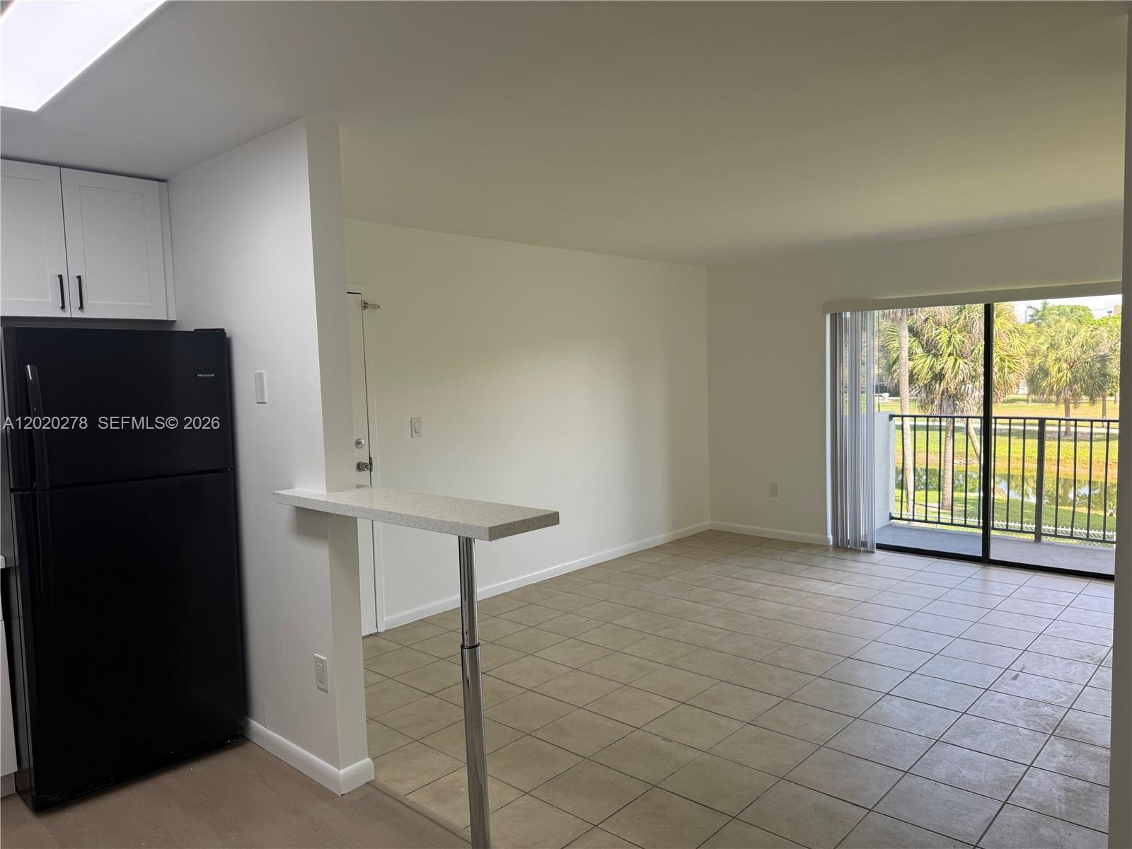 An open living area features tiled floors, a breakfast bar, and a sliding glass door — 7195 NW 179th St, Hialeah FL 33015, HIALEAH, FL