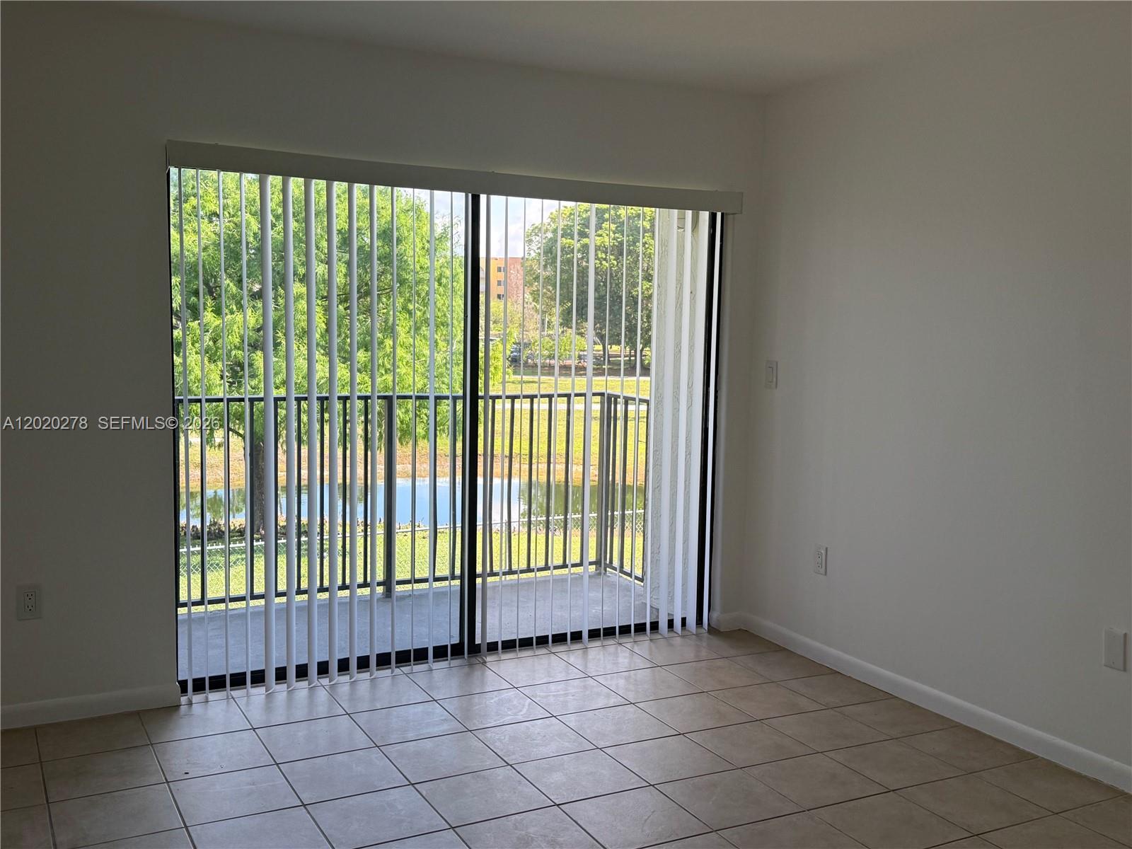 A room with tile flooring features a sliding glass door leading to a balcony — 7195 NW 179th St, Hialeah FL 33015, HIALEAH, FL