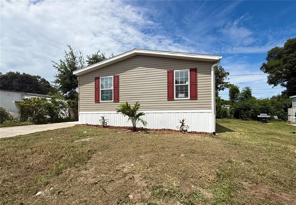 A single-story house with beige siding, red shutters, and a white foundation sits on grass — 37743 GEIGER ROAD, ZEPHYRHILLS, FL