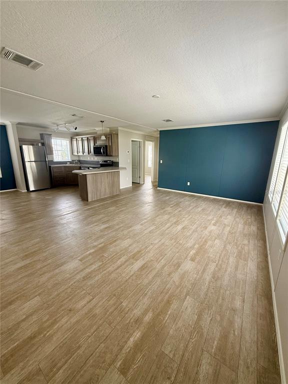 An open-concept living area features wood-look flooring, a kitchen with wood cabinets, and a blue wall — 37743 GEIGER ROAD, ZEPHYRHILLS, FL