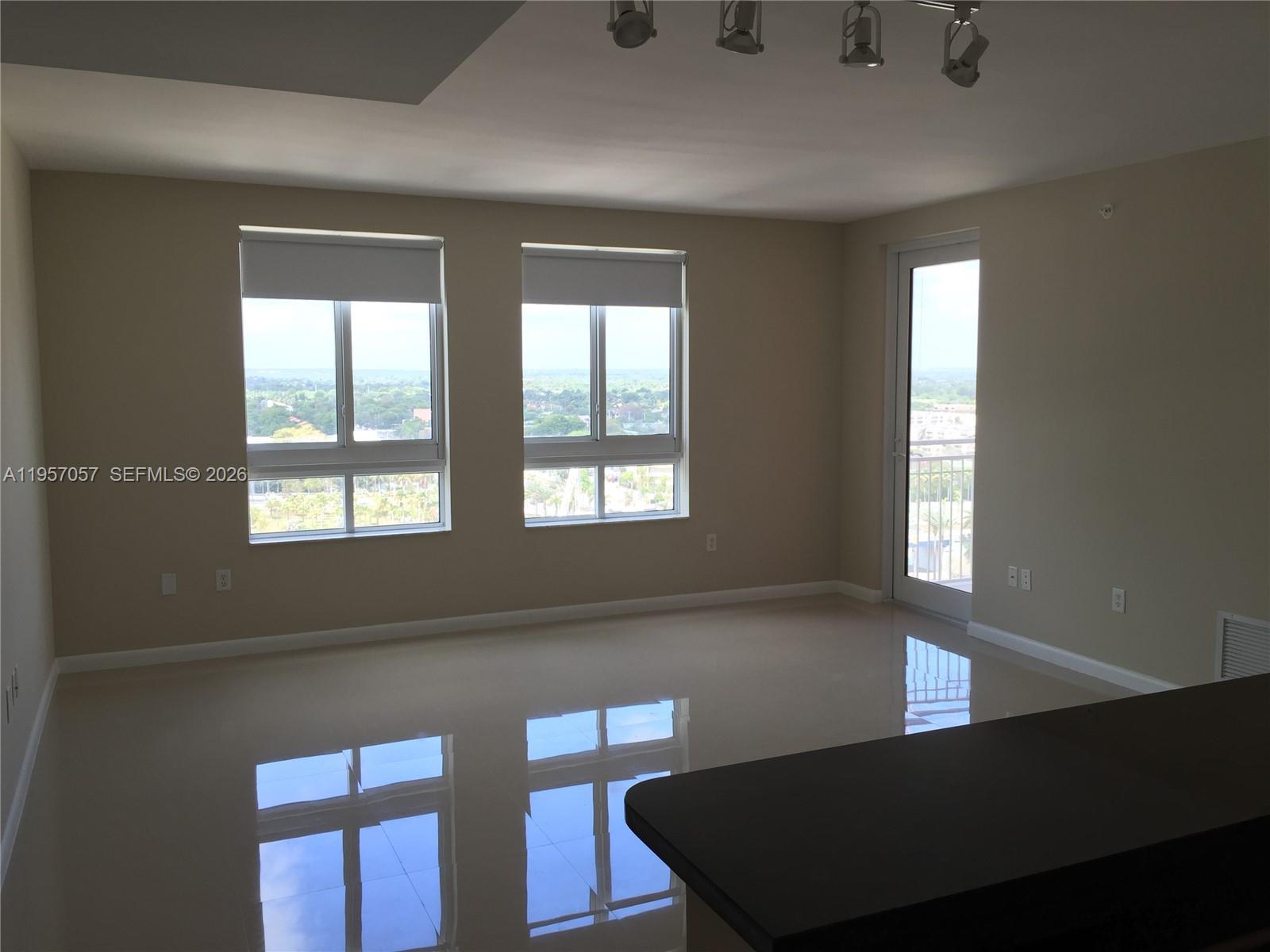 An empty room with glossy tile floors, large windows, and a balcony door — 7350 SW 89th St # 1611S, Miami FL 33156, MIAMI, FL