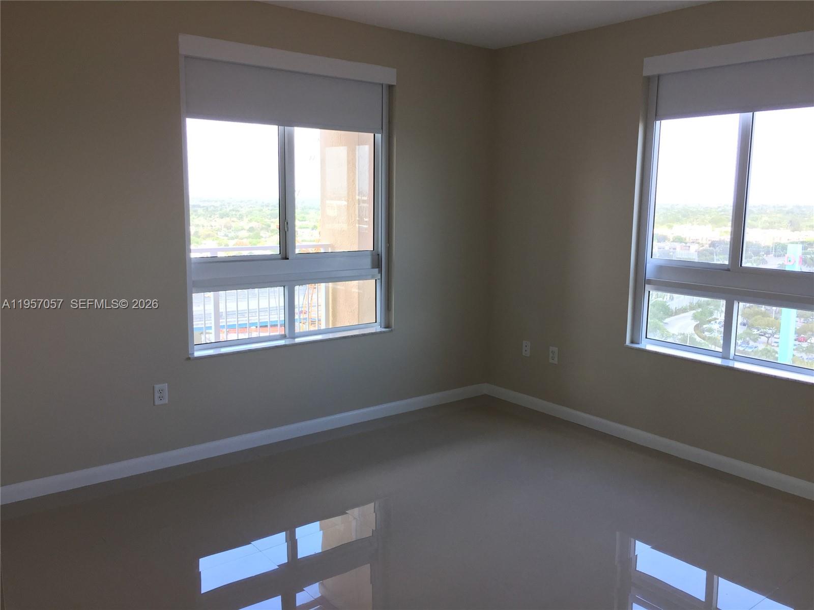 An empty room features beige walls, glossy tile floors, and two windows with roller shades — 7350 SW 89th St # 1611S, Miami FL 33156, MIAMI, FL