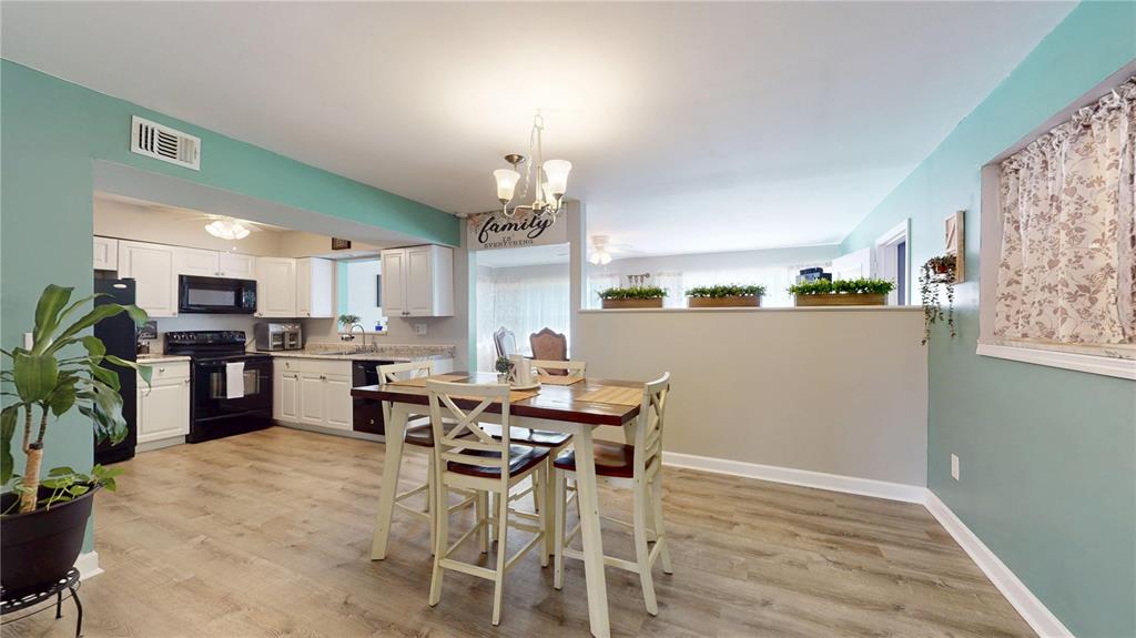 A kitchen and dining area with white cabinets, wood-look flooring, and teal walls — 20407 ALBURY DRIVE, PORT CHARLOTTE, FL