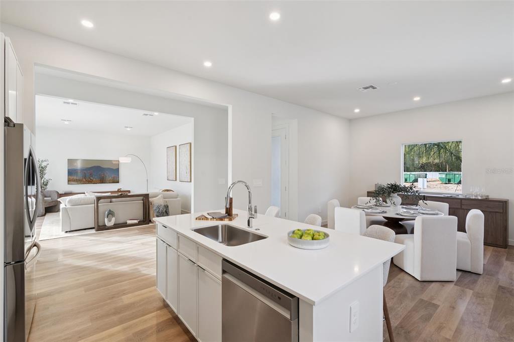 A modern kitchen with a white island and stainless steel appliances overlooks a dining area — 451 SKYFIELD COURT, LADY LAKE, FL