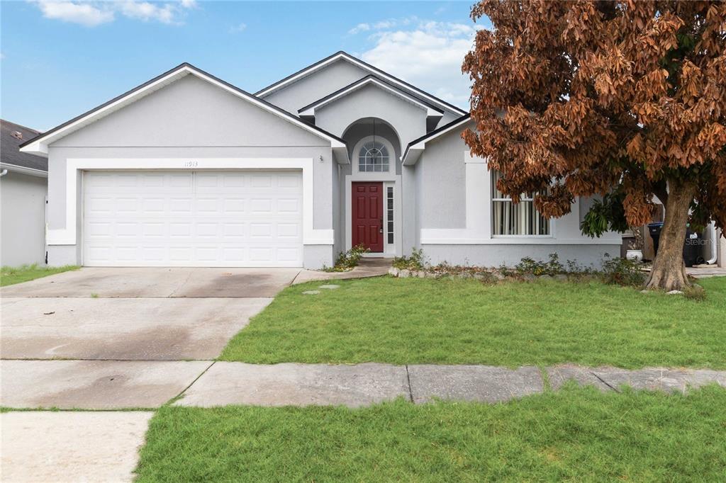 A single-story suburban house features a gray stucco exterior, a red front door, and a garage — 11913 HATCHER CIRCLE, ORLANDO, FL