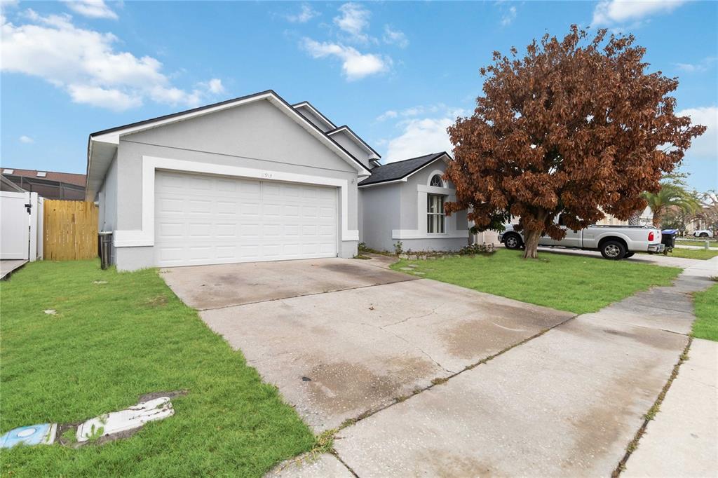 A single-story house with a white garage, gray stucco exterior, and a large brown tree — 11913 HATCHER CIRCLE, ORLANDO, FL