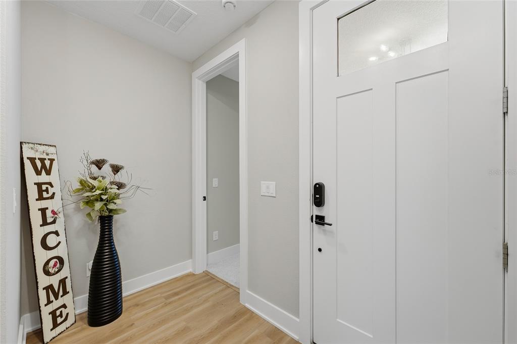 An entryway features light wood flooring, a white door, and a vertical welcome sign — 17222 DANCY ORANGE COURT, WINTER GARDEN, FL