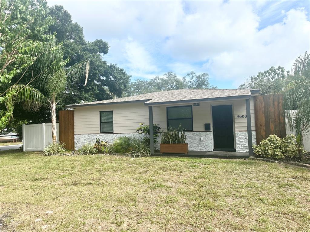 A single-story house features light siding, white stone accents, and a dark front door — 4600 30TH AVENUE N, ST PETERSBURG, FL
