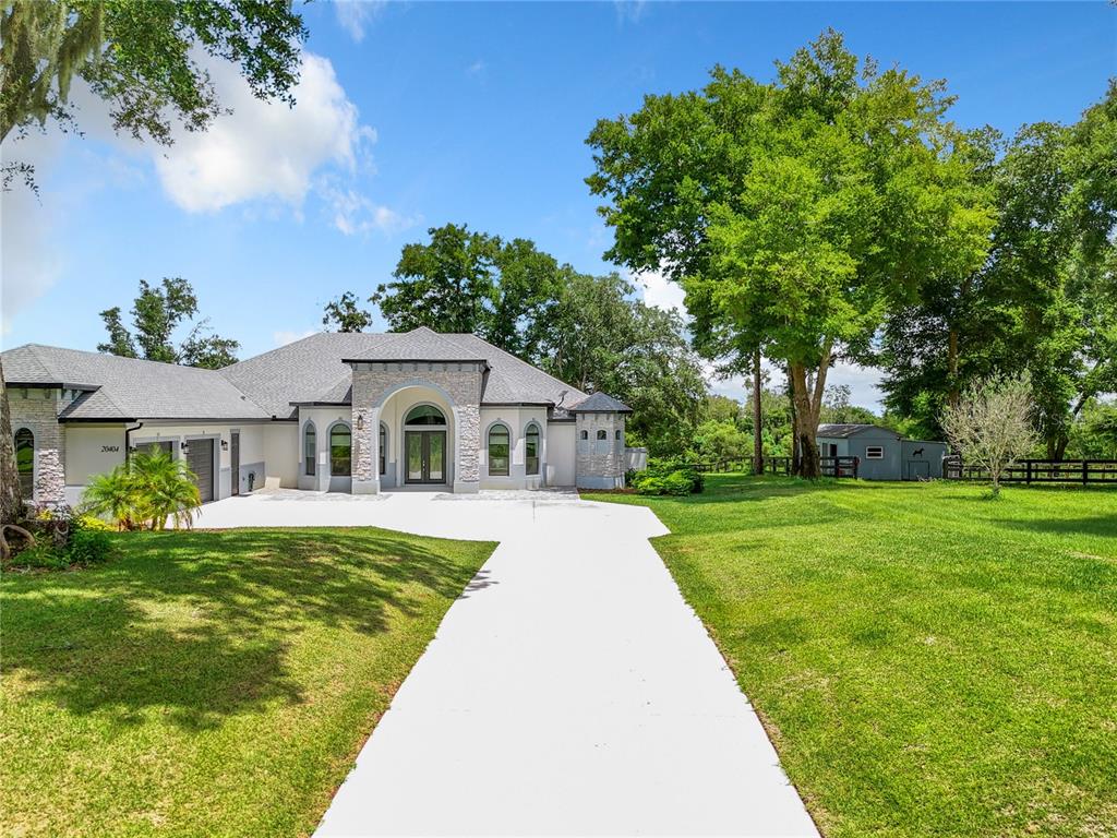 A single-story house with a stone facade and arched entryway sits on a grassy lot — 20404 WOLF SPRINGS COURT, CLERMONT, FL