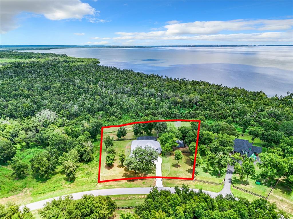 An aerial view shows a house with a red outline situated near a large lake — 20404 WOLF SPRINGS COURT, CLERMONT, FL