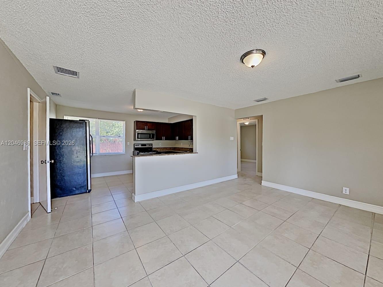 A tiled living area opens to a kitchen with dark cabinets and a breakfast bar — FORT LAUDERDALE, FL