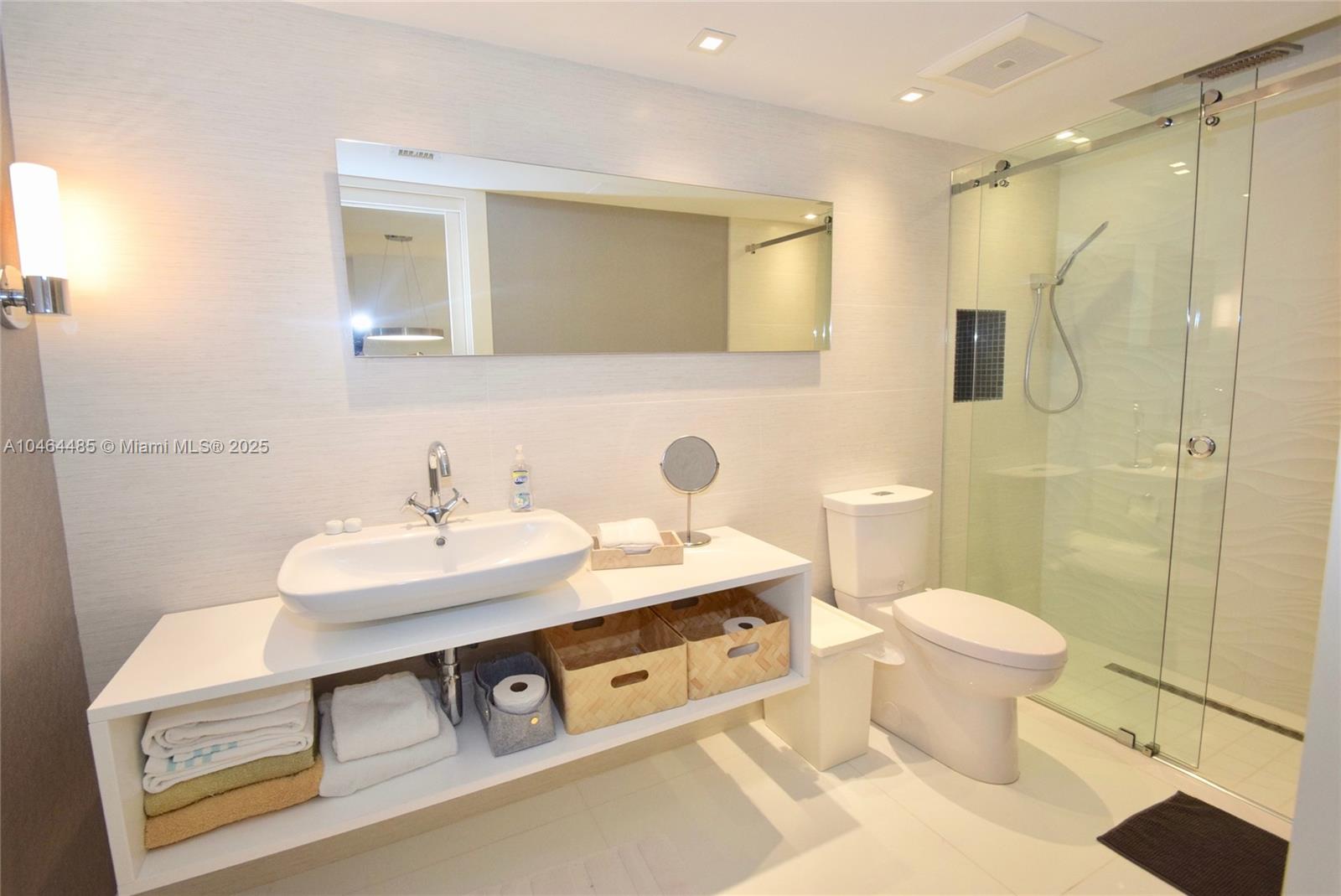 A modern bathroom features a white vessel sink, open shelving, a toilet, and a glass shower — 2301 Collins Ave, Miami Beach FL 33139, MIAMI BEACH, FL