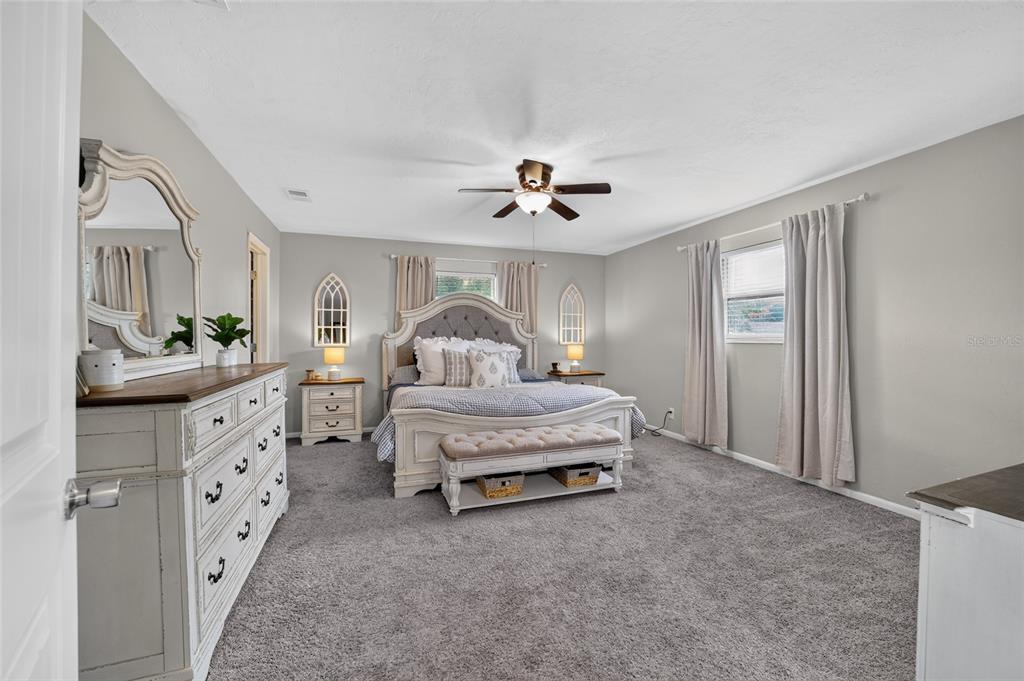 A bedroom features a white upholstered bed, a matching dresser with a mirror, and gray carpeting — 1861 SE 56TH COURT, OCALA, FL