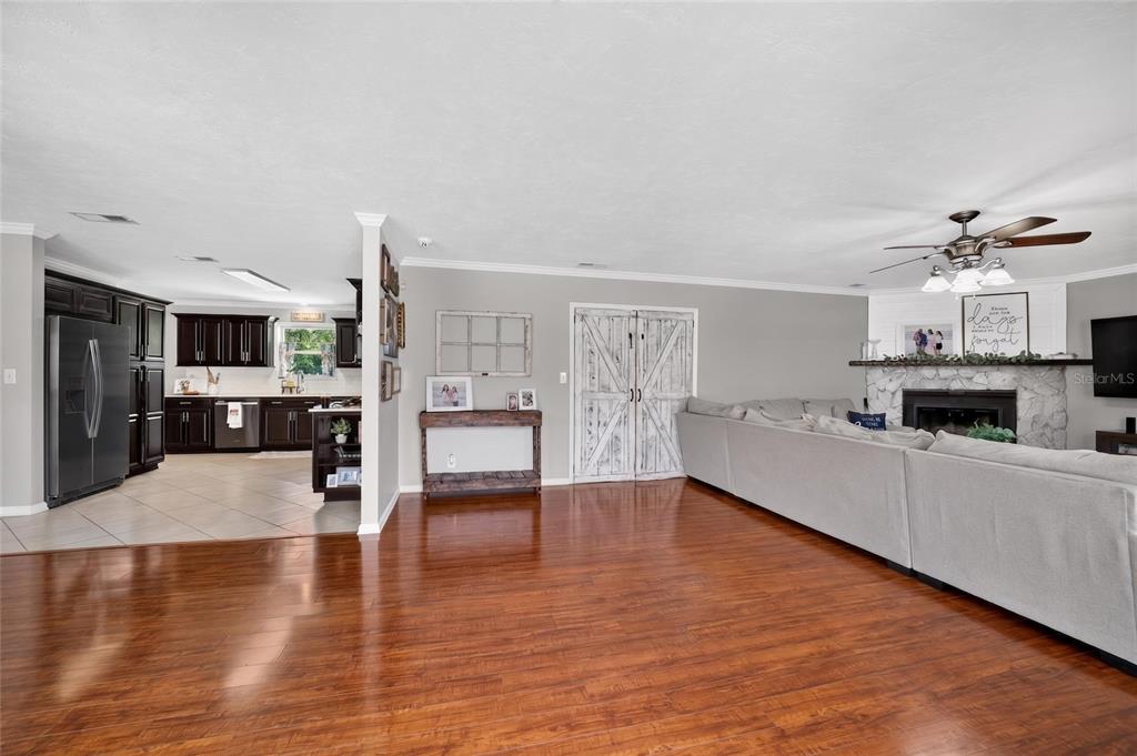 A living room with hardwood floors and a fireplace connects to a dark-cabinet kitchen — 1861 SE 56TH COURT, OCALA, FL