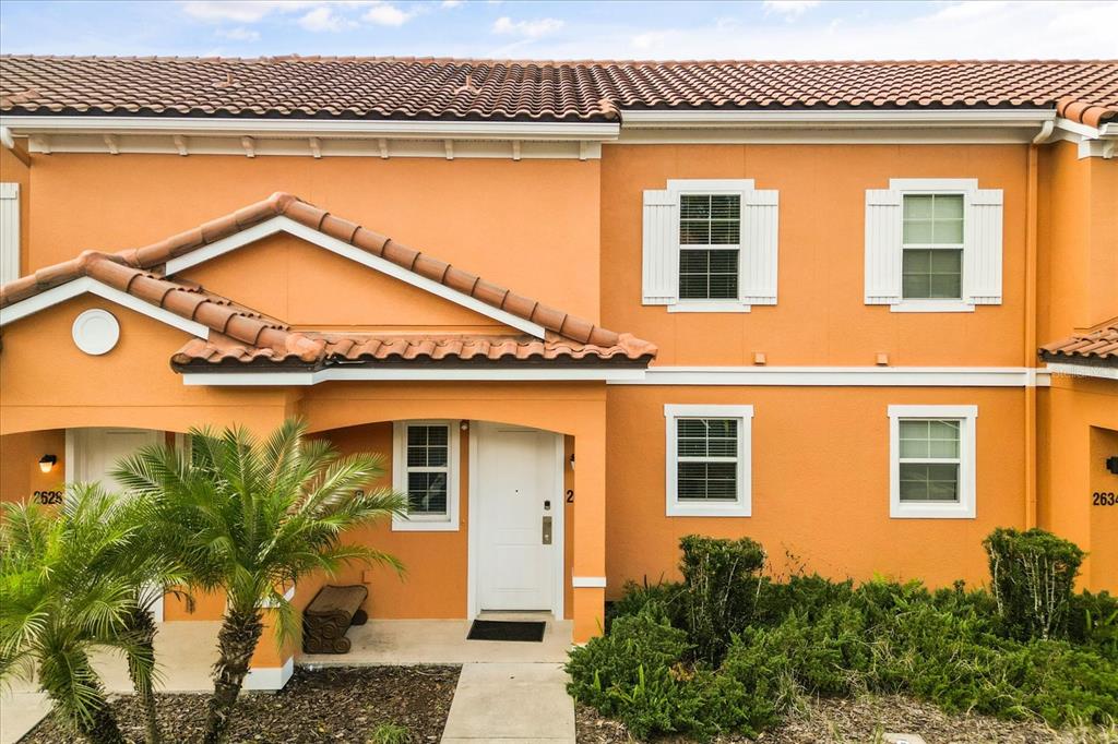 The exterior of an orange two-story townhouse features a tiled roof and white window shutters — 2630 CORVETTE LANE, KISSIMMEE, FL