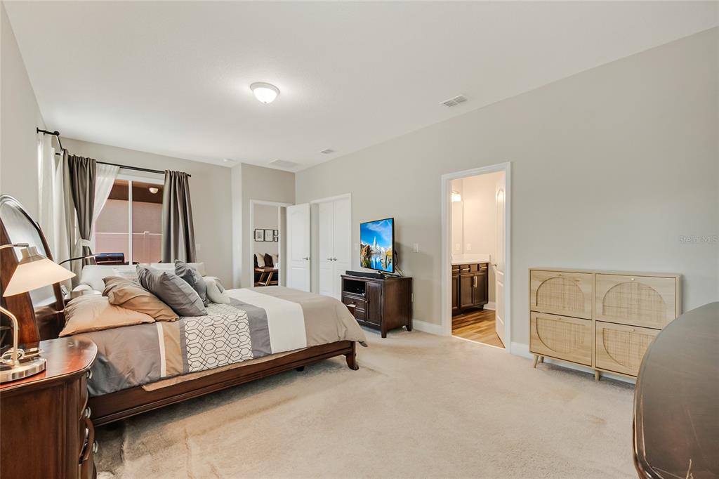 A bedroom features a bed, a television on a stand, and an attached bathroom — 12278 NORTHOVER LOOP, ORLANDO, FL
