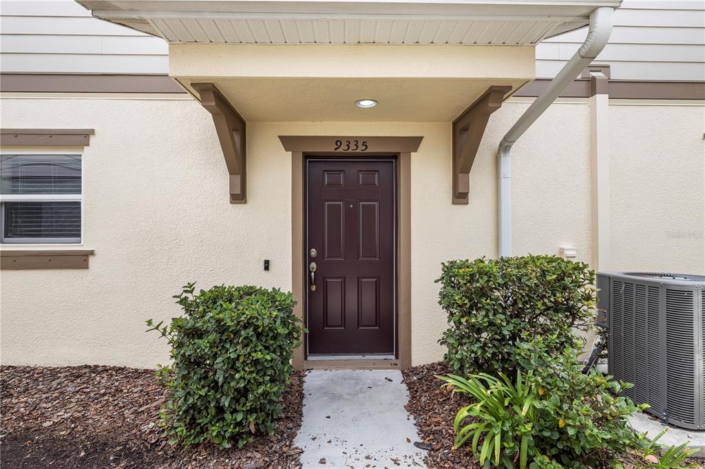 The exterior of a residential unit features a brown front door under a small porch — 9335 AMERICAN HICKORY LANE, RIVERVIEW, FL