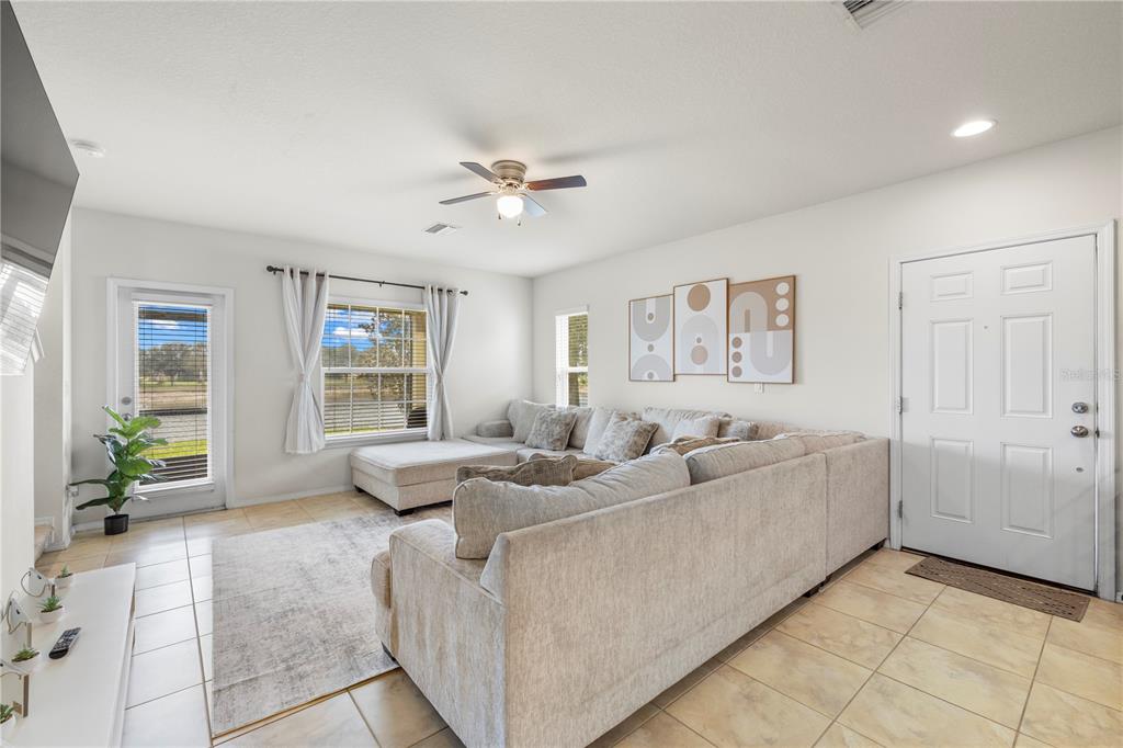 A living room features a large sectional sofa, tile flooring, and a glass door — 9335 AMERICAN HICKORY LANE, RIVERVIEW, FL
