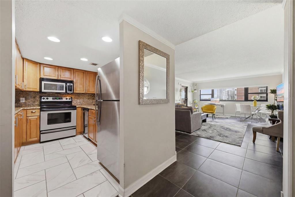 A kitchen with stainless steel appliances and light tile floors opens into a living area — 4141 BAYSHORE BOULEVARD UNIT 706, TAMPA, FL