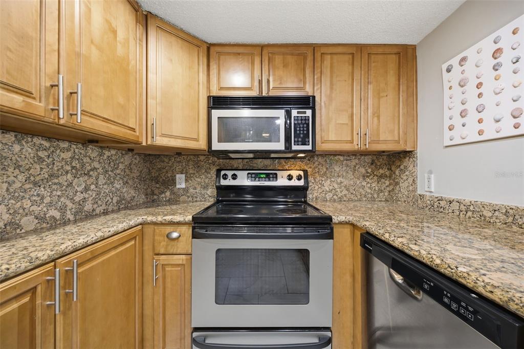 A kitchen features light wood cabinets, granite countertops, and stainless steel appliances — 4141 BAYSHORE BOULEVARD UNIT 706, TAMPA, FL