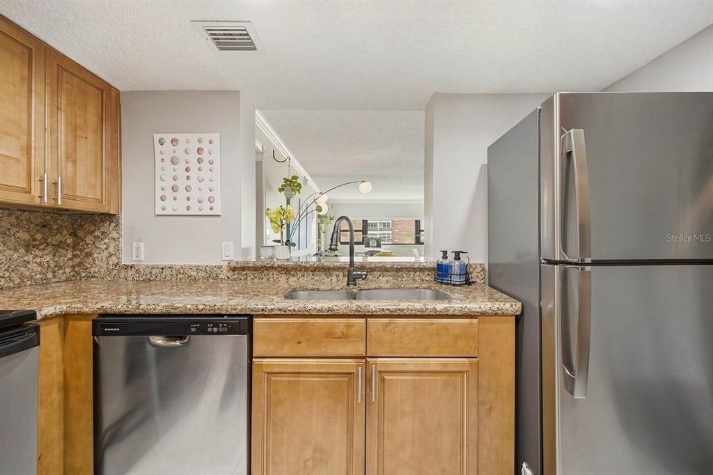 A kitchen features light wood cabinets, granite countertops, stainless steel appliances, and a pass-through window — 4141 BAYSHORE BOULEVARD UNIT 706, TAMPA, FL