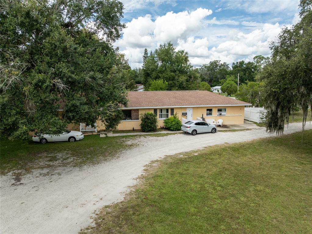 A single-story yellow house with a brown roof sits on a large grassy lot — 124 S CHARLES RICHARD BEALL BOULEVARD, DEBARY, FL