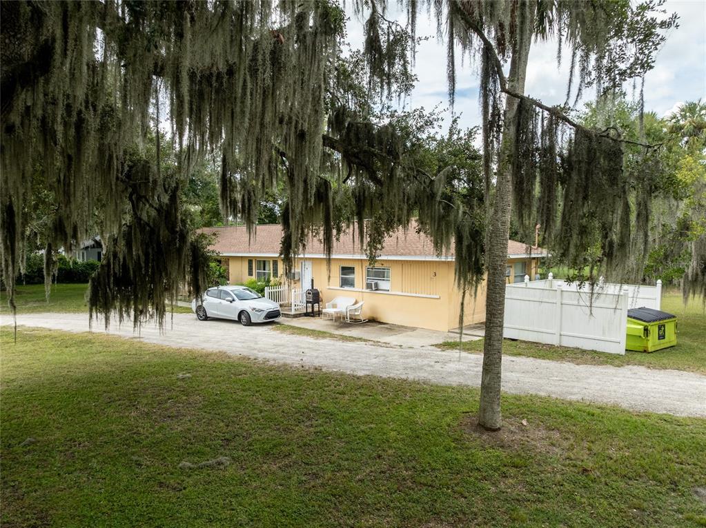 A single-story yellow house with a white fence and a car parked in the driveway — 124 S CHARLES RICHARD BEALL BOULEVARD, DEBARY, FL