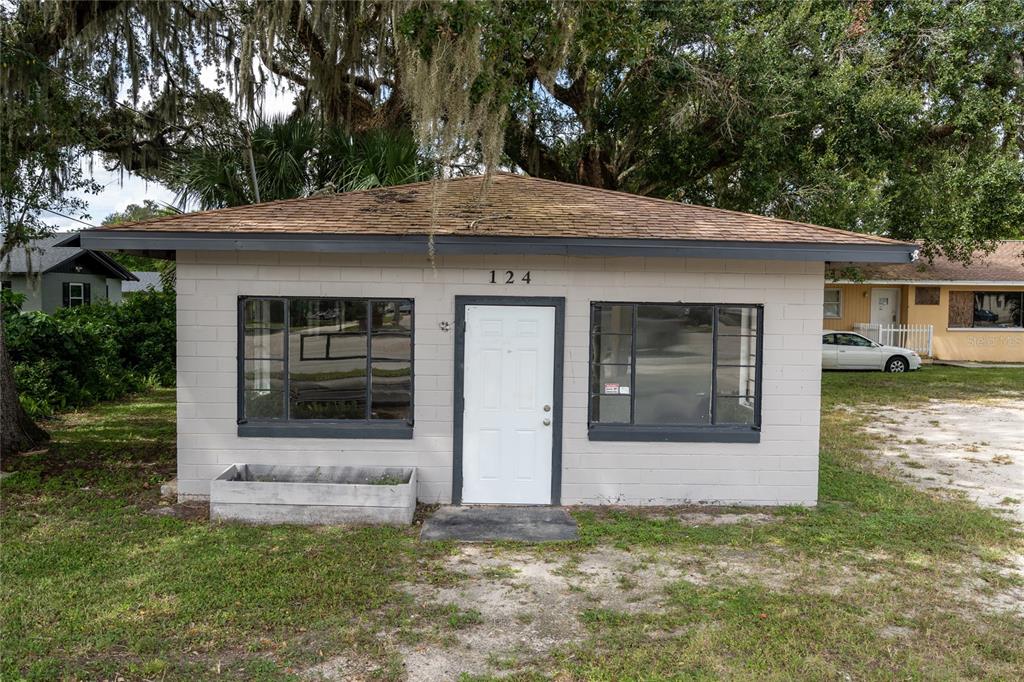 A small, single-story concrete block building with a white door and two large windows — 124 S CHARLES RICHARD BEALL BOULEVARD, DEBARY, FL