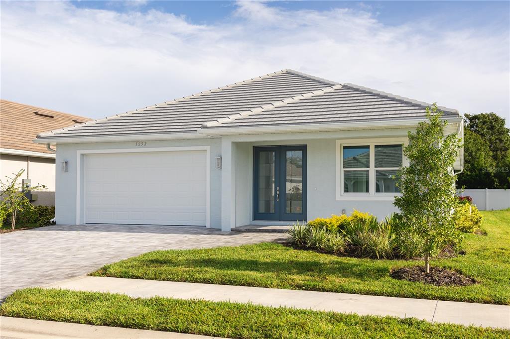 A single-story house with a light blue exterior, a two-car garage, and a tiled roof — 5213 WILLOW LAKE COURT, SARASOTA, FL