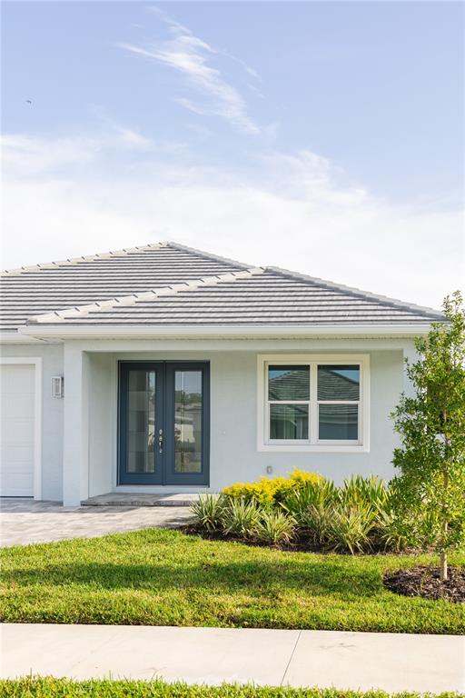 The exterior of a light-colored house features a dark blue double front door and landscaping — 5213 WILLOW LAKE COURT, SARASOTA, FL
