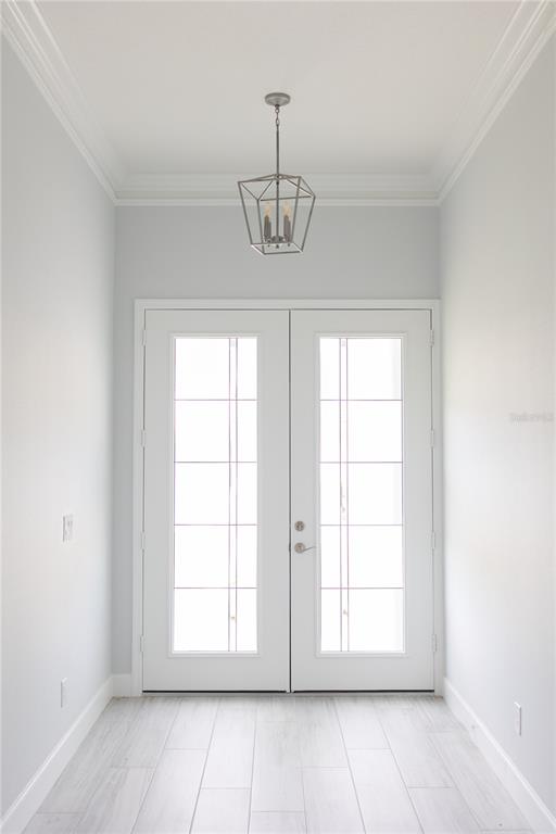 A bright entryway features double glass-paneled doors, light-colored tile flooring, and a geometric pendant light — 5213 WILLOW LAKE COURT, SARASOTA, FL